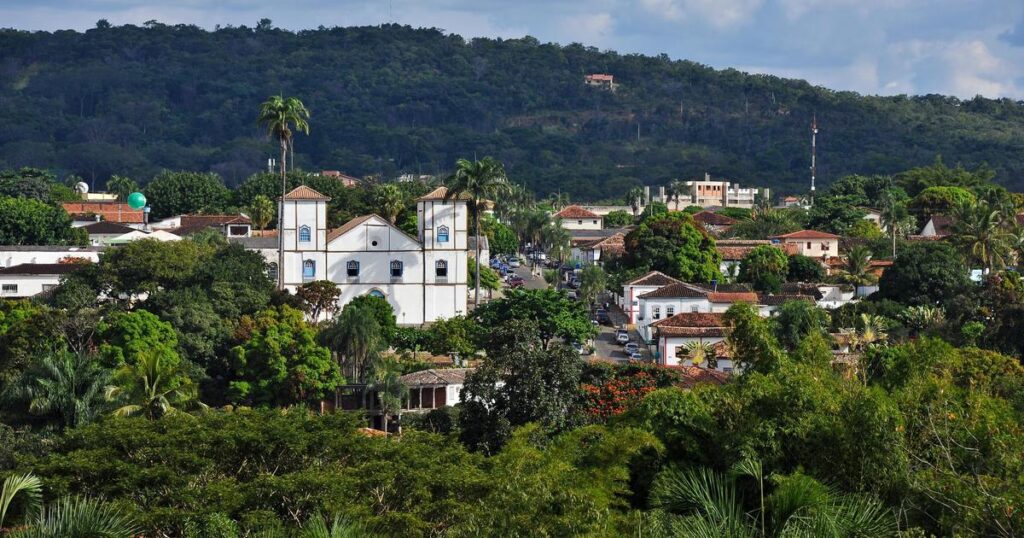 Vista panorâmica do centro histórico de Pirenópolis, destacando a Igreja Matriz branca e a densa vegetação verde das montanhas ao fundo, mostrando o charme colonial da cidade em Goiás.