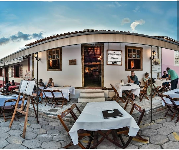 Fachada do restaurante Empório, em casa colonial branca, com mesas e clientes sentados ao ar livre na calçada, ilustrando a gastronomia de rua de Pirenópolis.