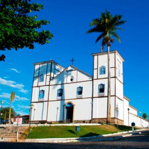 Igreja Matriz de Nossa Senhora do Rosário, com fachada branca e detalhes azuis e duas torres, sob céu limpo. Ponto turístico e arquitetura colonial de Pirenópolis.